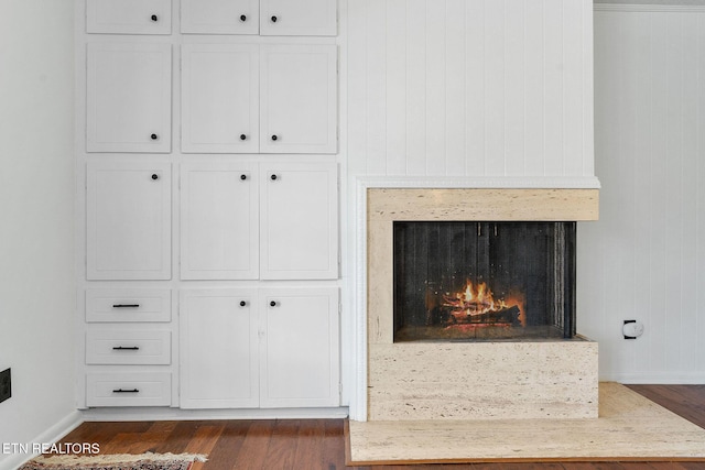 interior details with a large fireplace, wood finished floors, and baseboards