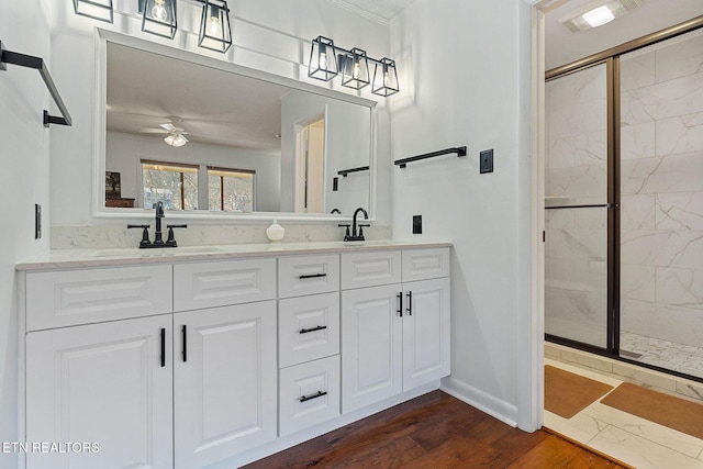 bathroom featuring double vanity, a stall shower, visible vents, wood finished floors, and a sink