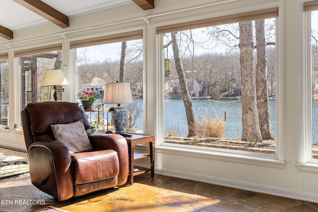 sitting room featuring dark wood-type flooring, a water view, beamed ceiling, and baseboards