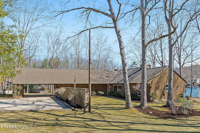 view of front of property featuring driveway, a front lawn, and a water view