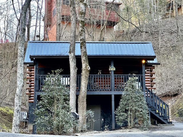 exterior space featuring stairs, metal roof, and log siding