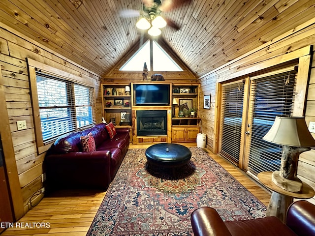 living area featuring wooden ceiling, wood walls, a fireplace, and vaulted ceiling