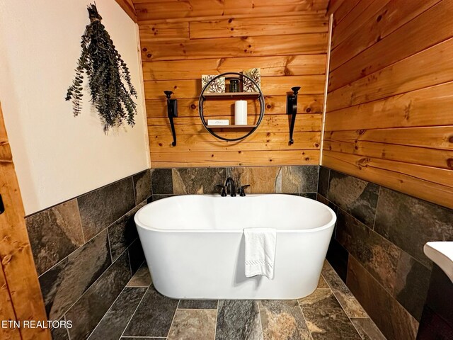 831 Bear Run Way, Sevierville, TN 37862 - bathroom featuring stone tile flooring, a freestanding bath, wood walls, and tile walls