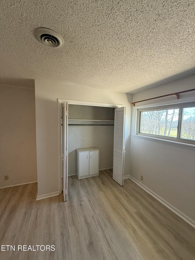 7000 Big Horn Dr Unit A-3, Crossville, TN 38572 - unfurnished bedroom featuring a textured ceiling, visible vents, a closet, and wood finished floors