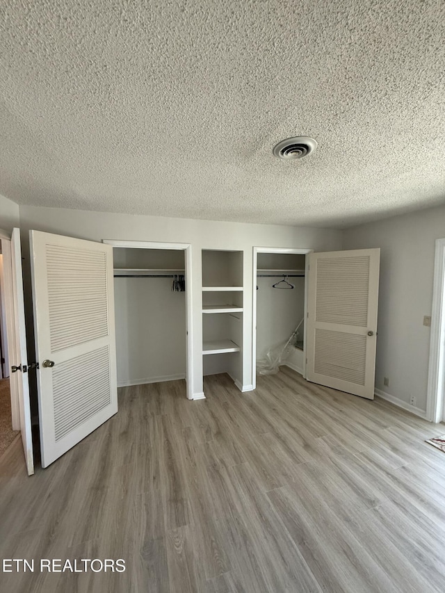 7000 Big Horn Dr Unit A-3, Crossville, TN 38572 - unfurnished bedroom with a textured ceiling, wood finished floors, visible vents, baseboards, and two closets
