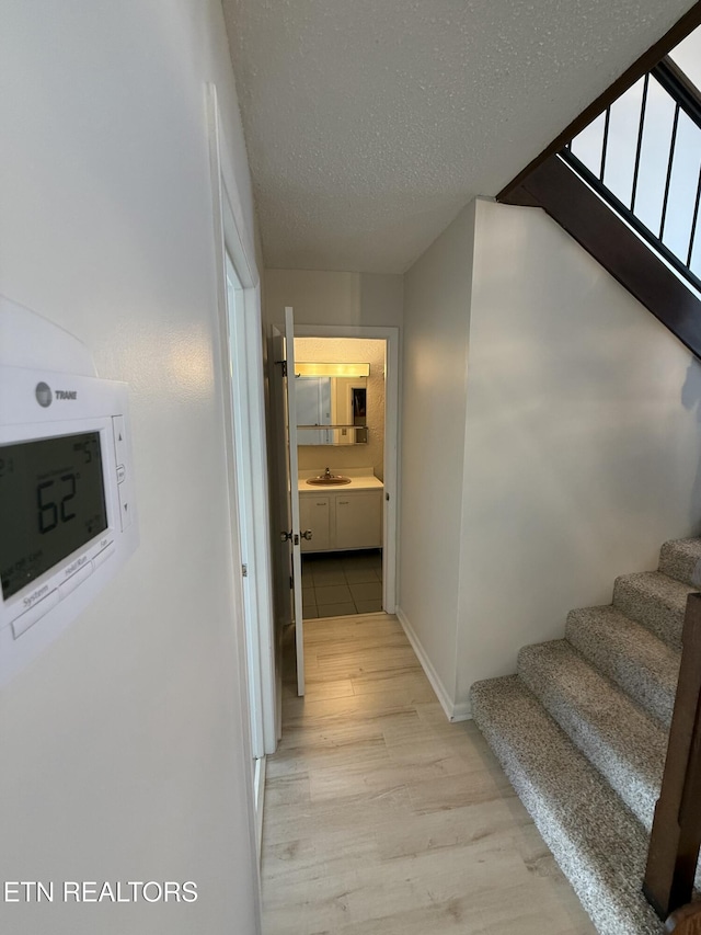 7000 Big Horn Dr Unit A-3, Crossville, TN 38572 - hallway with light wood finished floors, a sink, a textured ceiling, baseboards, and stairs