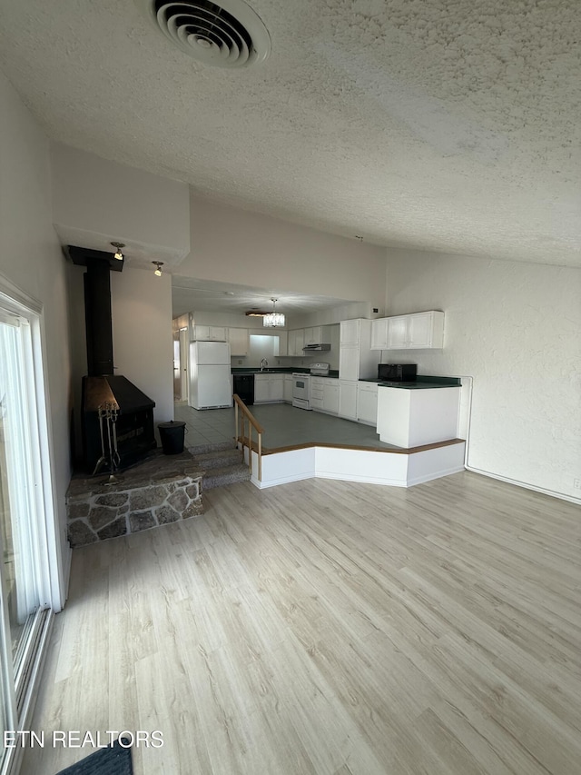 7000 Big Horn Dr Unit A-3, Crossville, TN 38572 - unfurnished living room with visible vents, a wood stove, vaulted ceiling, a textured ceiling, and light wood-style floors