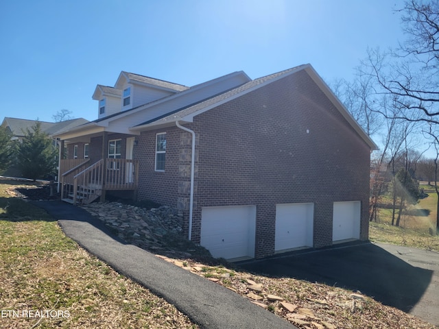 view of home's exterior with a garage, driveway, and brick siding