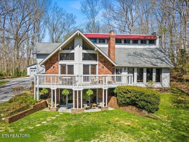 rear view of house with a deck, a lawn, a garage, and a chimney