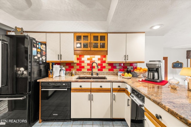 kitchen featuring black appliances, a sink, light stone counters, a textured ceiling, and white cabinetry