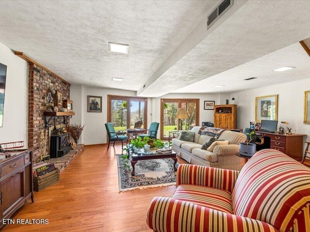 living area with visible vents, a textured ceiling, and light wood-type flooring