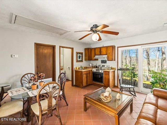 kitchen featuring under cabinet range hood, range with electric cooktop, brown cabinetry, and light countertops