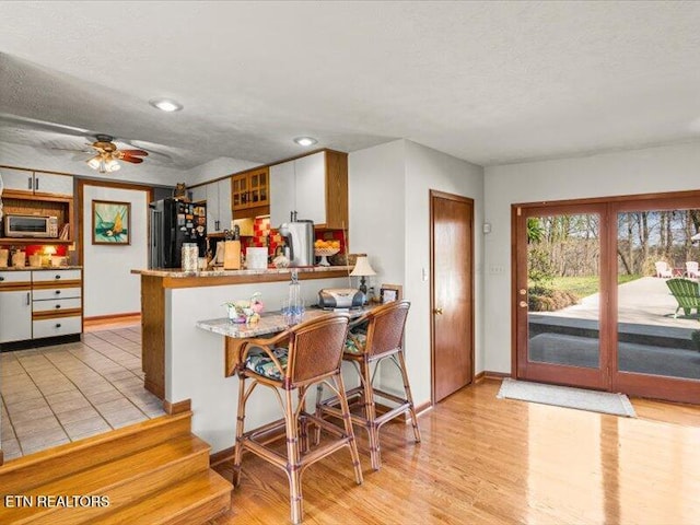 kitchen featuring stainless steel microwave, a ceiling fan, freestanding refrigerator, and a textured ceiling