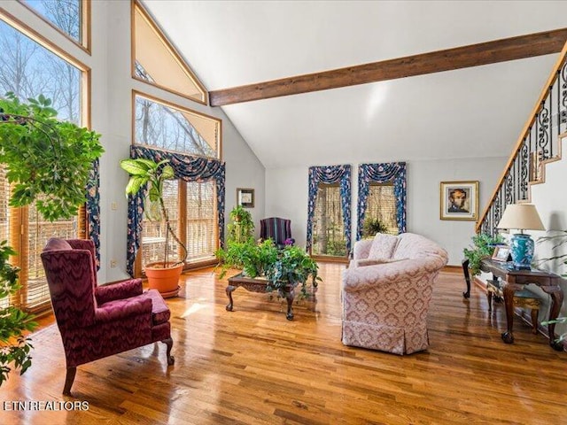 living area with beam ceiling, stairway, wood finished floors, and high vaulted ceiling