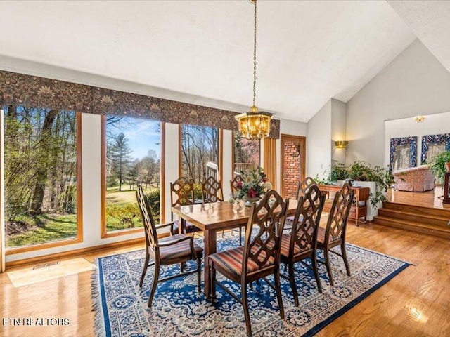 dining space featuring a chandelier, high vaulted ceiling, and wood finished floors