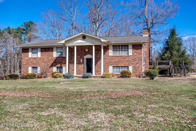 view of front of home featuring a front yard, brick siding, and a chimney