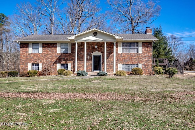 view of front facade with brick siding, a chimney, and a front lawn