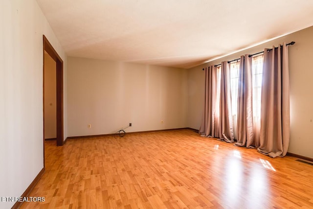 spare room with light wood-style flooring, visible vents, and baseboards