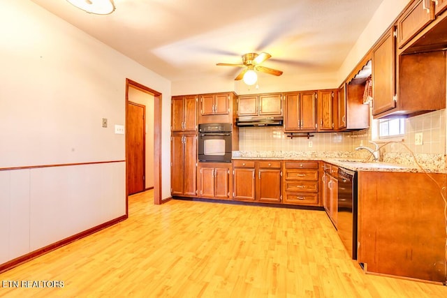 kitchen with brown cabinets, under cabinet range hood, black appliances, and light wood finished floors