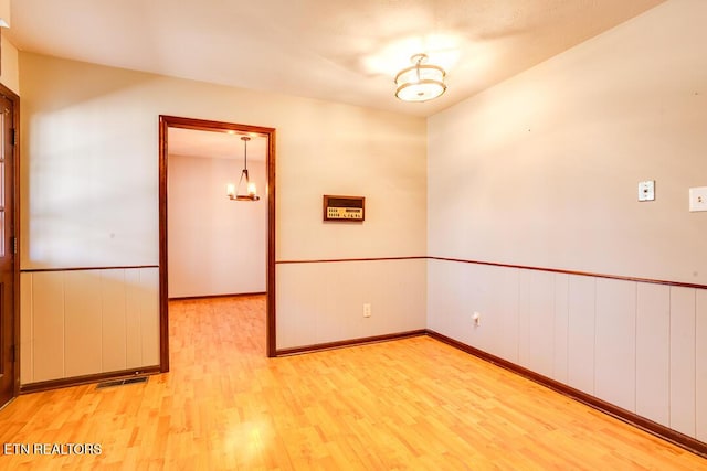 empty room with visible vents, wainscoting, and light wood-style flooring