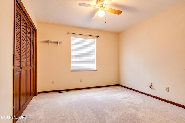 unfurnished bedroom with a ceiling fan, a closet, light colored carpet, and baseboards