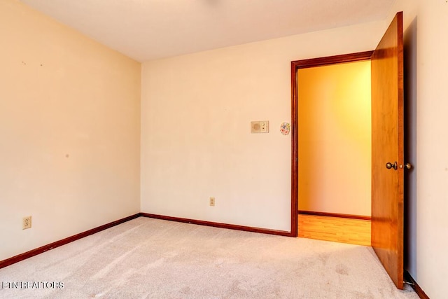 unfurnished room with light carpet and baseboards