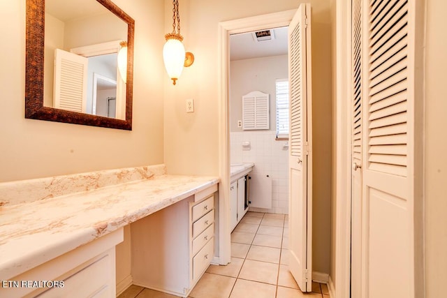 bathroom featuring tile patterned flooring, visible vents, vanity, tile walls, and a closet