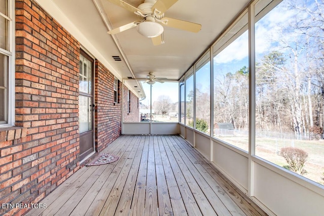 unfurnished sunroom with visible vents and a ceiling fan