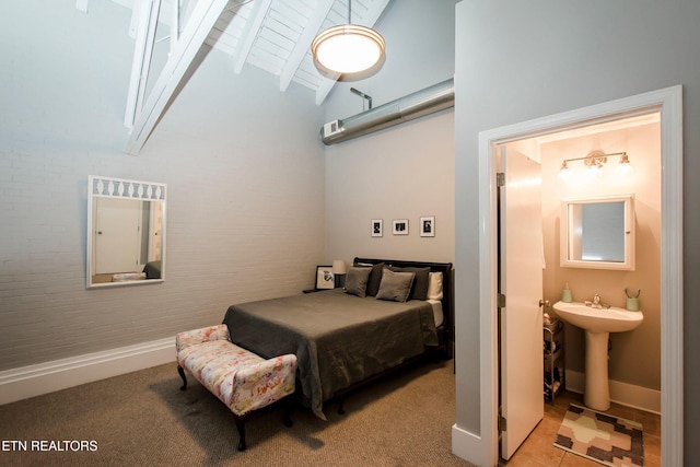 carpeted bedroom with baseboards, ensuite bathroom, beam ceiling, high vaulted ceiling, and a sink