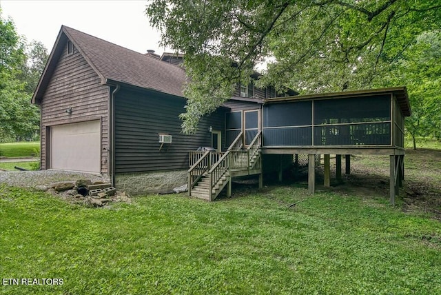 rear view of property featuring a garage, a sunroom, a yard, and roof with shingles