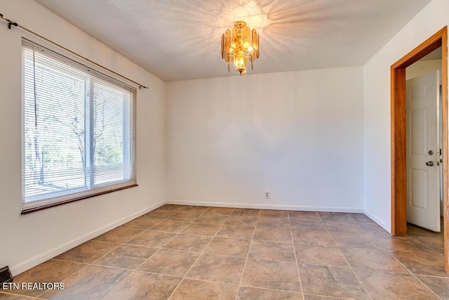 unfurnished room featuring a chandelier, visible vents, a textured ceiling, and baseboards