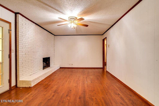 unfurnished living room with a textured ceiling, ornamental molding, and wood finished floors