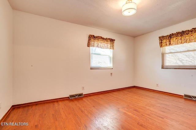 unfurnished room with visible vents, baseboards, and wood finished floors