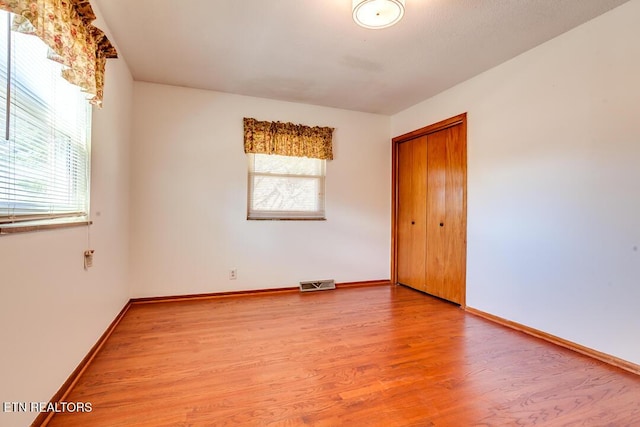 unfurnished room with visible vents, baseboards, and wood finished floors