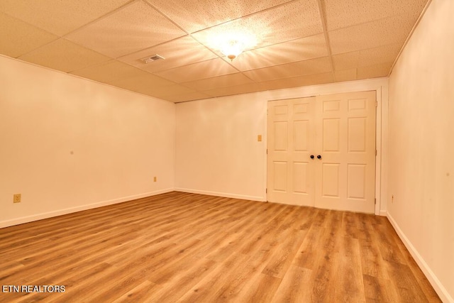 empty room with light wood-style flooring, a paneled ceiling, visible vents, and baseboards