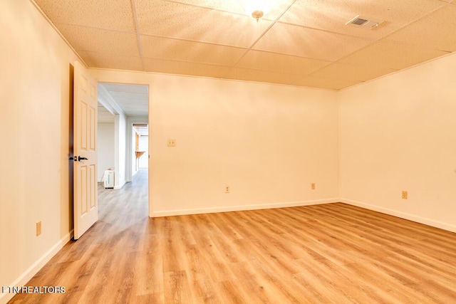 empty room with a paneled ceiling, light wood finished floors, and baseboards