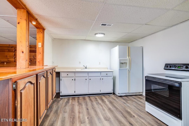 kitchen with electric stove, white refrigerator with ice dispenser, light countertops, visible vents, and a sink