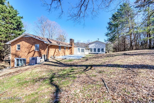 back of house with central AC, brick siding, and a patio