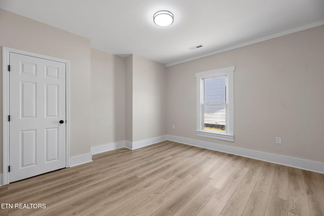 unfurnished room with visible vents, light wood-style flooring, and baseboards