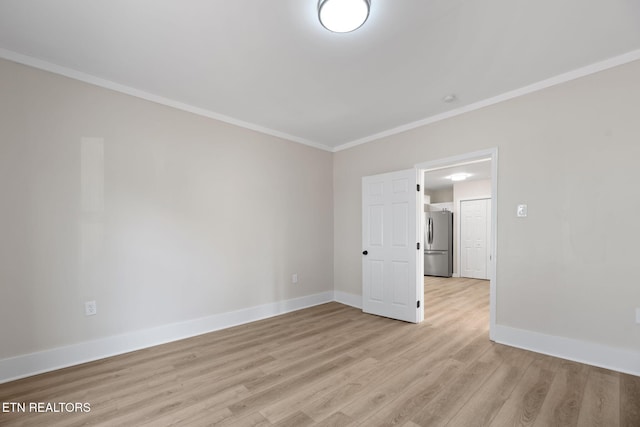 spare room with crown molding, light wood-style flooring, and baseboards