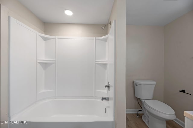 bathroom featuring toilet, washtub / shower combination, baseboards, and wood finished floors