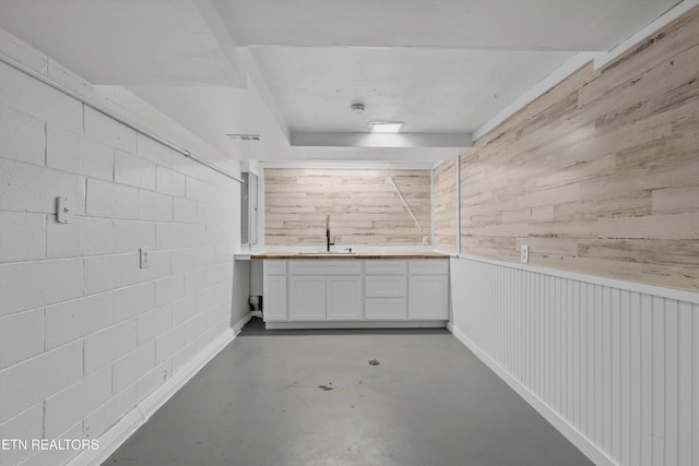 basement featuring concrete block wall, wood walls, visible vents, and a sink