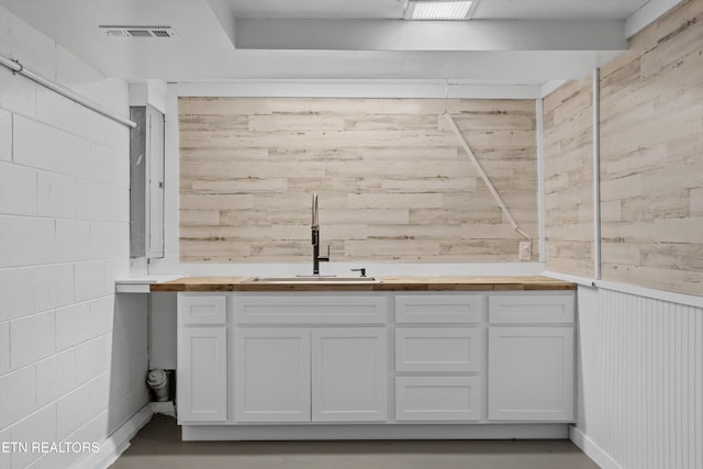 bathroom with concrete block wall, wooden walls, visible vents, and vanity