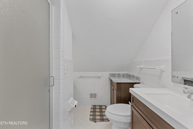 full bath with visible vents, vaulted ceiling, tile walls, and vanity