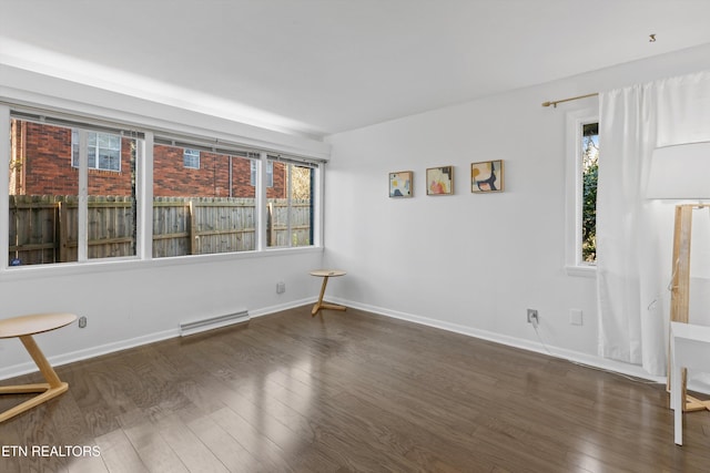 spare room featuring a baseboard radiator, baseboards, and wood finished floors