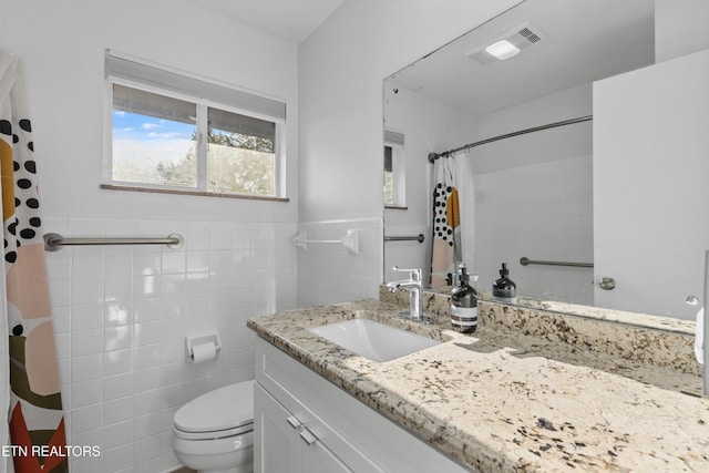 full bathroom with curtained shower, toilet, a wainscoted wall, visible vents, and tile walls