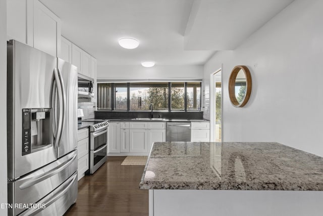 kitchen with a sink, white cabinets, appliances with stainless steel finishes, backsplash, and dark wood finished floors