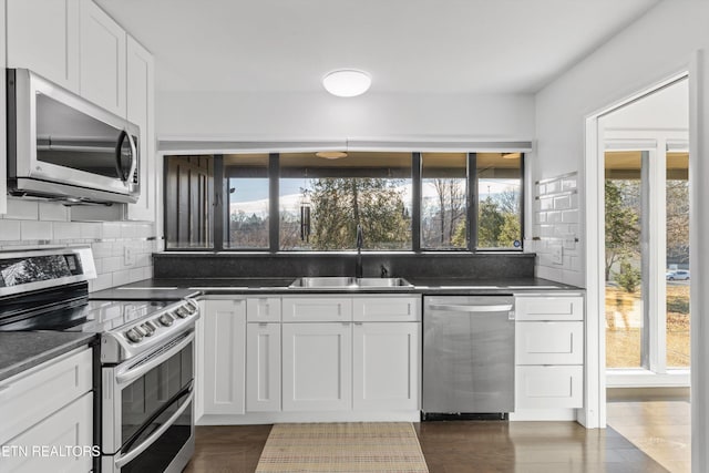 kitchen with stainless steel appliances, white cabinetry, a sink, and tasteful backsplash