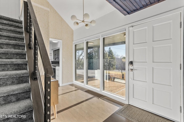 doorway to outside featuring light wood-style flooring, a sink, vaulted ceiling, stairs, and an inviting chandelier