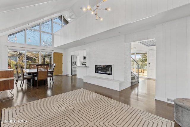 living area featuring a large fireplace, a healthy amount of sunlight, and dark wood-style flooring